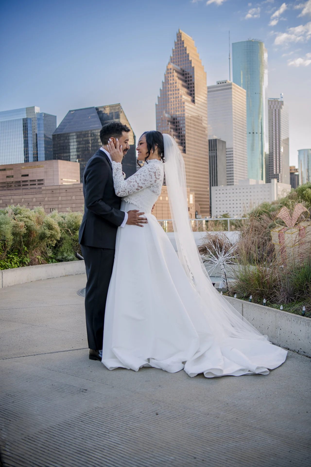 Newlyweds sharing their first kiss beneath greenery and a chandelier.