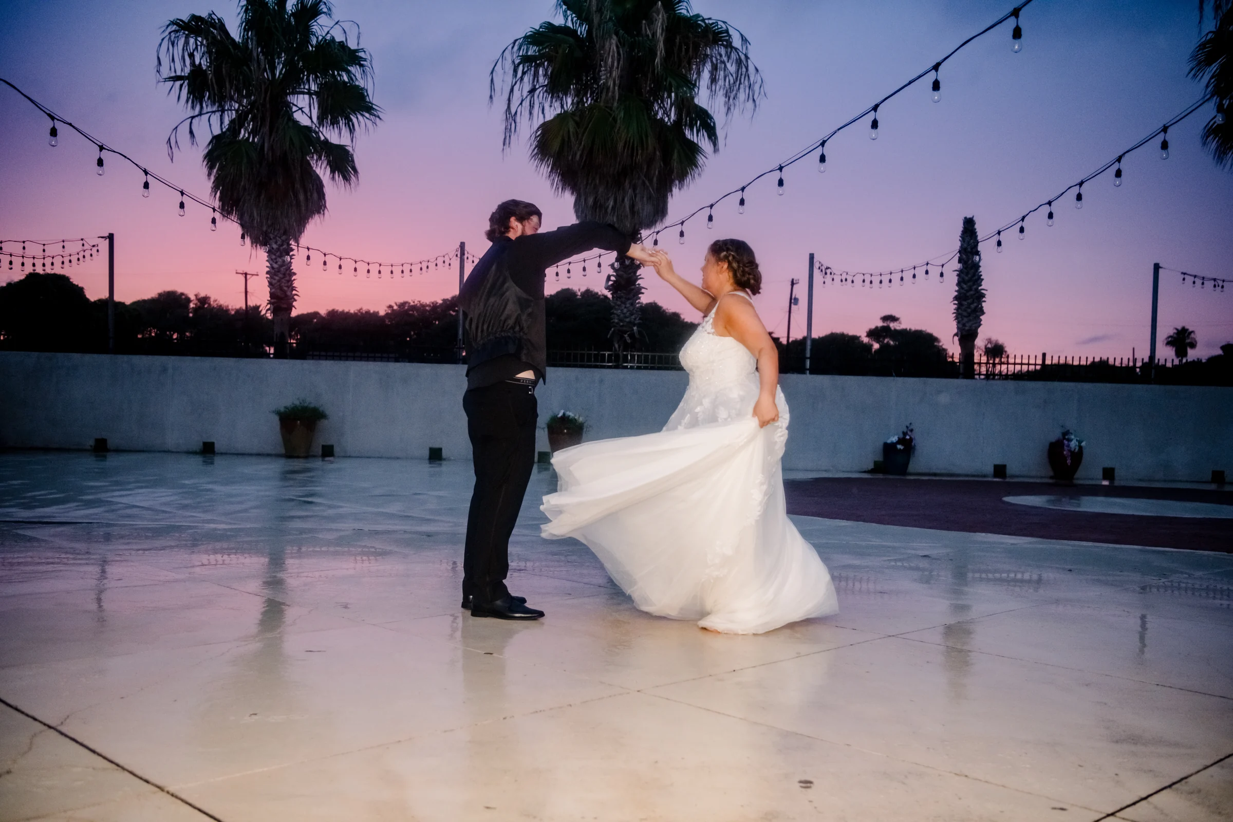 Newlyweds dancing together at sunset.