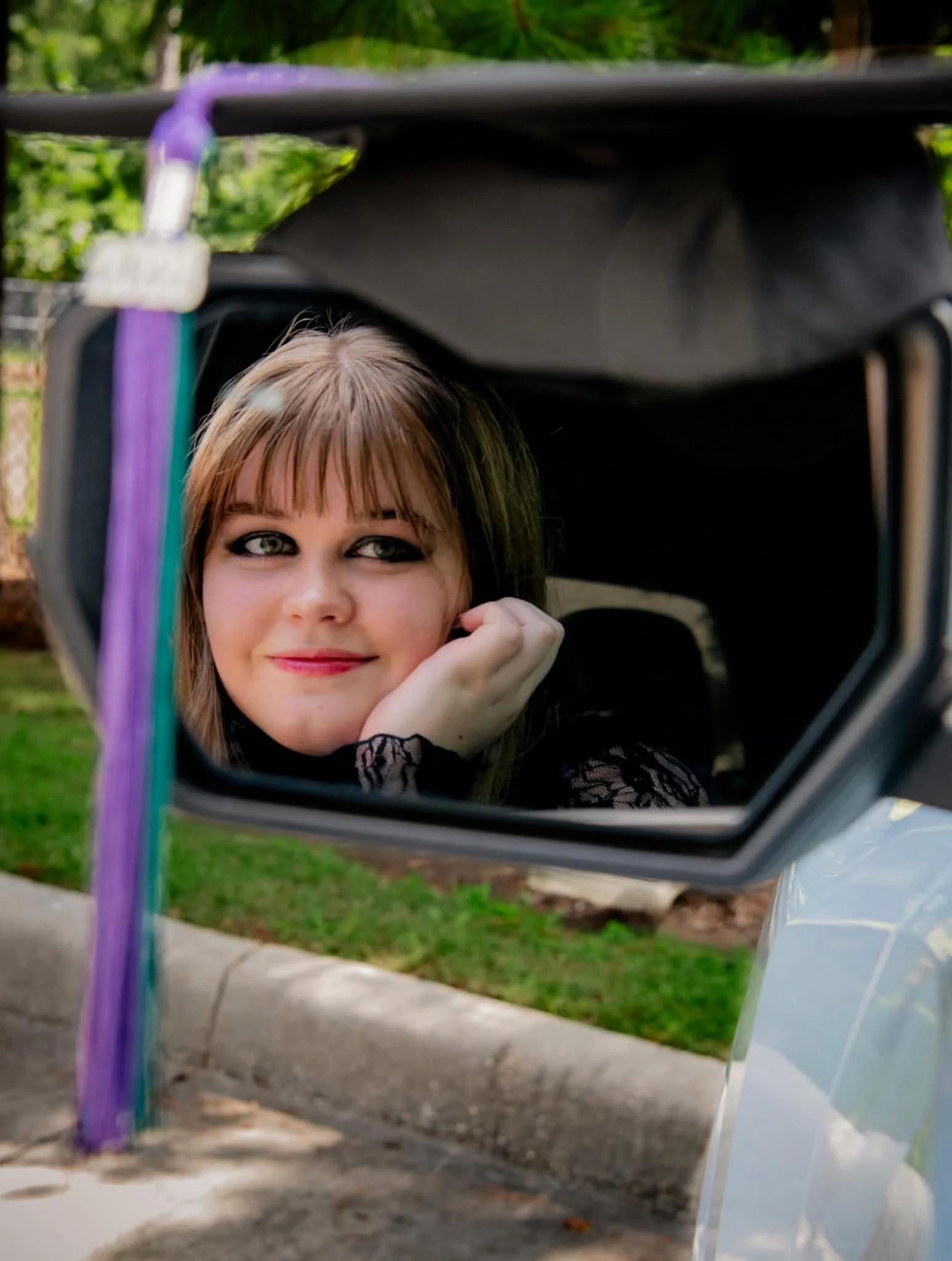 Senior portrait reflected in a vehicle mirror.